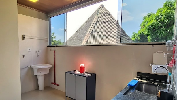 Una cocina moderna con encimera negra, cocina a gas, fregadero y ventana con vistas a una casa.