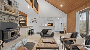 A spacious living area with a stone fireplace, leather sofas, and a wooden coffee table.