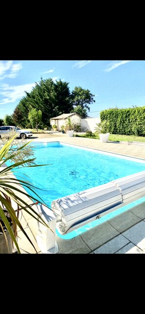 A swimming pool with a tiled deck, surrounded by greenery and a stone building. - Beautiful air-conditioned country villa, sleeps 10, with saltwater pool. (Manosque)