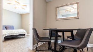 Un dormitorio con cama, ventilador de techo y zona de comedor con mesa y sillas.