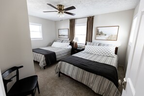 A bedroom with two beds, a ceiling fan, a nightstand, a chair, and two framed pictures on the wall. - Allsports lakehouse w/private beach/dock, firepit, grill, sunset view! (Belding)