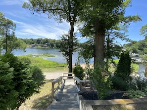 Una escalera de madera que conduce a un muelle junto a un lago, rodeado de follaje y árboles.
