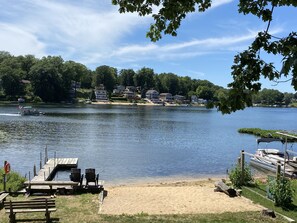 A lakeside view with a dock, chairs, and a picnic table. - Allsports lakehouse w/private beach/dock, firepit, grill, sunset view! (Belding)