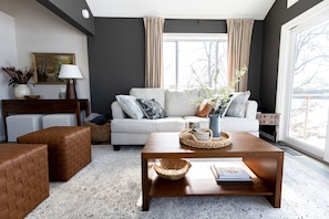 A modern living room with a sofa, coffee table, and ottoman.