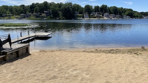 Vista de un lago con un muelle de madera y una playa arenosa.