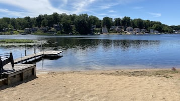 Vista de un lago con un muelle de madera y una playa arenosa.