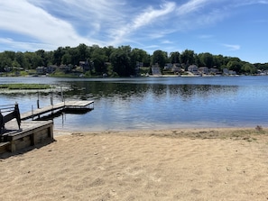 Vista de un lago con un muelle de madera y una playa arenosa.