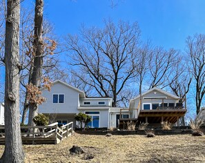 A two-story house with a front deck and a garage. - Allsports lakehouse w/private beach/dock, firepit, grill, sunset view! (Belding)
