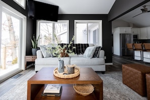 A modern living room with a sofa, coffee table, and kitchen in the background.
