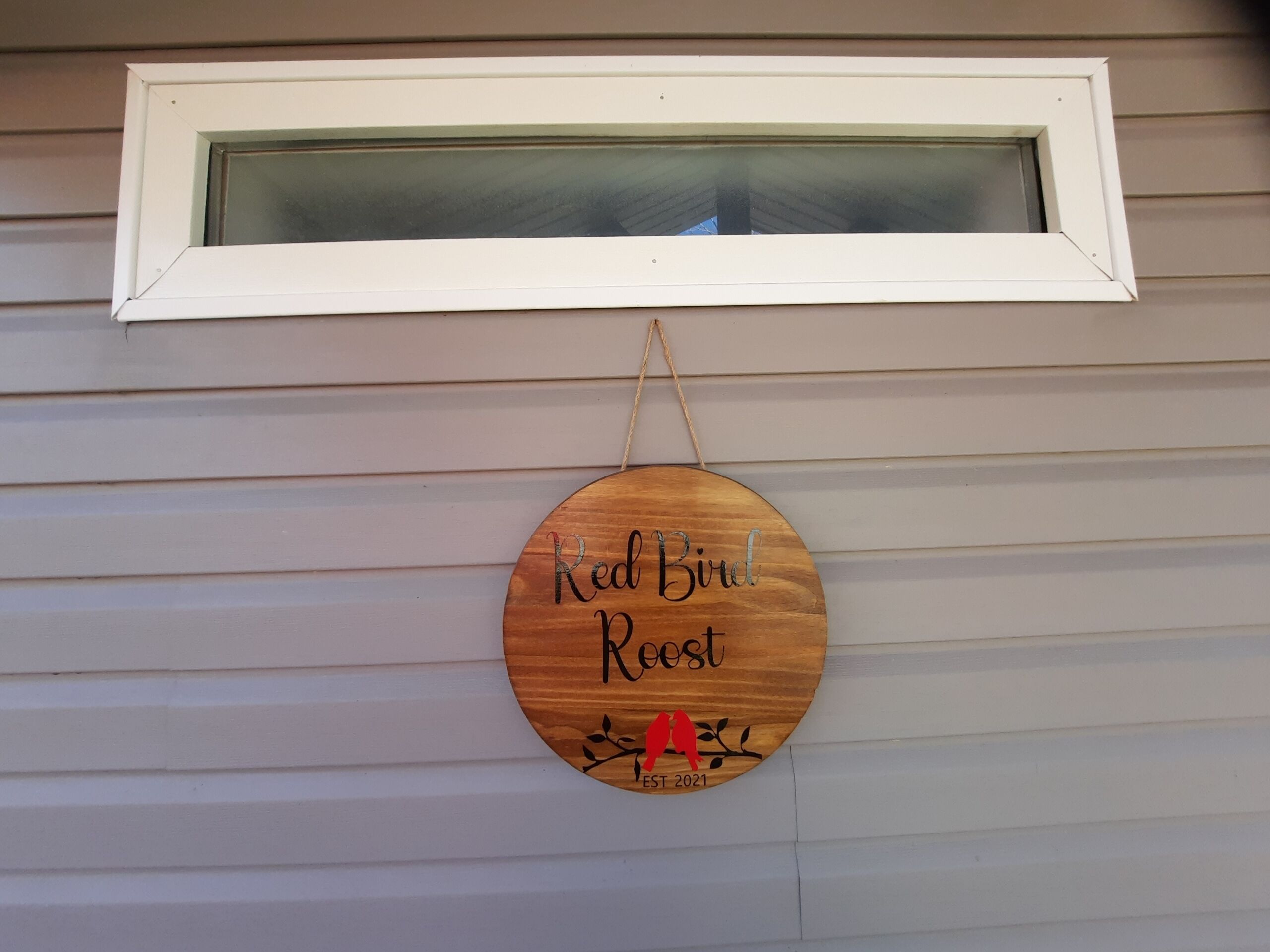 Puinen kyltti, jossa lukee ”Red Bird Rec” ja on kuvattuna lintu, on ripustettu ikkunan alle taloon.