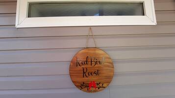 Puinen kyltti, jossa lukee ”Red Bird Rec” ja on kuvattuna lintu, on ripustettu ikkunan alle taloon.