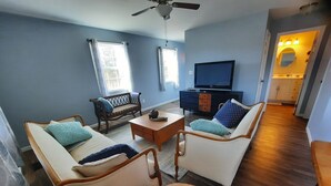 Un salon avec deux canapés, une table basse, un téléviseur et un ventilateur de plafond.