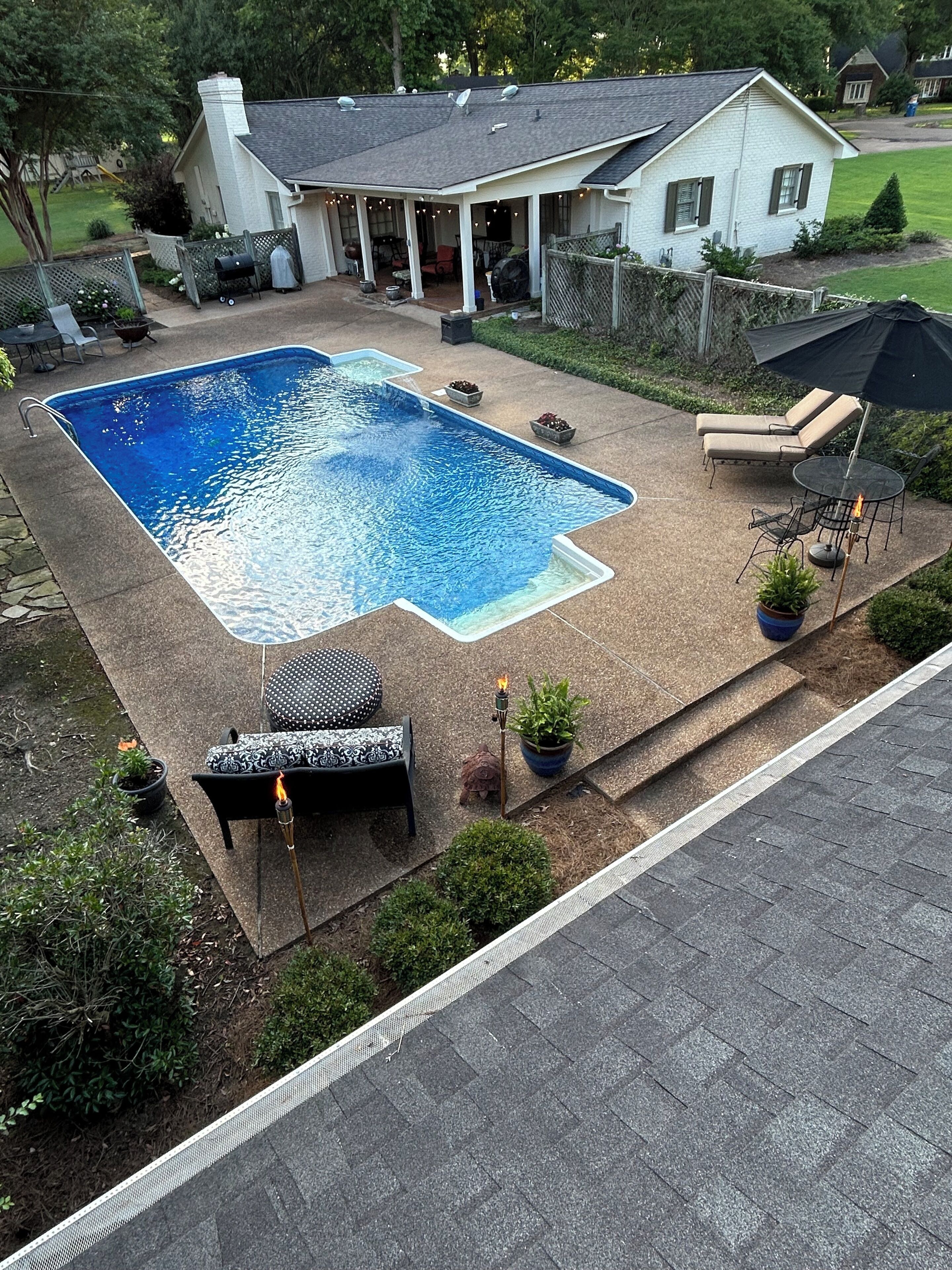 A backyard with a swimming pool, outdoor furniture, and a covered patio area.