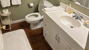 Un baño con inodoro, lavamanos y un cuadro en la pared.
