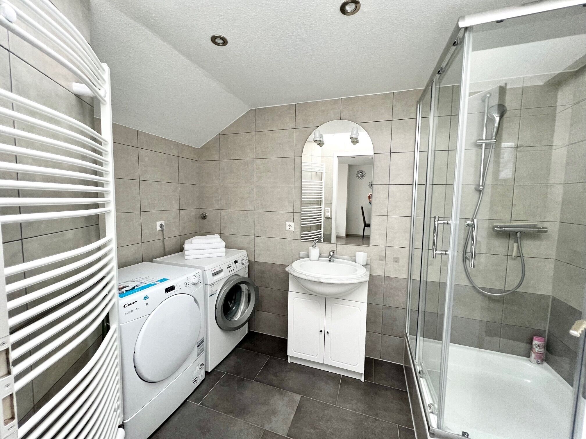 Un baño moderno con lavadora, lavamanos y ducha.