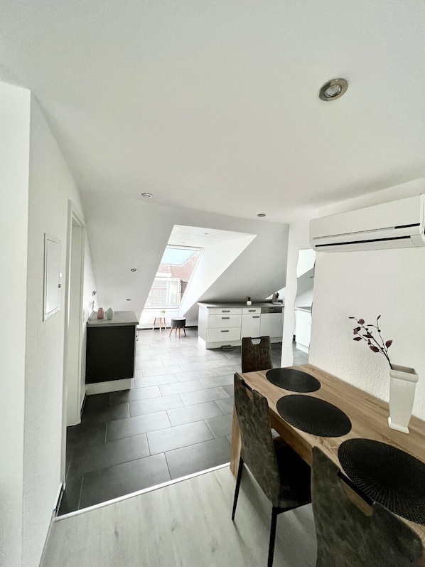 A modern kitchen with a skylight, a dining area with a wooden table and chairs, and a white kitchen counter.