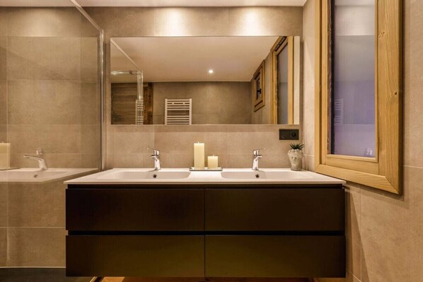 Un baño moderno con tocador doble, un espejo grande y una ventana con marco de madera.