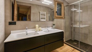 Un baño moderno con dos lavamanos, un espejo grande y una cabina de ducha de vidrio.