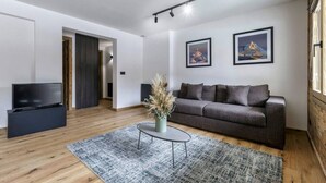 A modern living room with a grey sofa, a flat-screen TV, and a decorative vase.