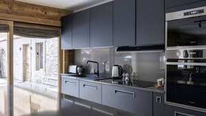 A modern kitchen with grey cabinets, a stainless steel range hood, and a built-in oven.