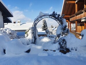 A snow-covered wooden building with a snow-covered archway in the foreground.