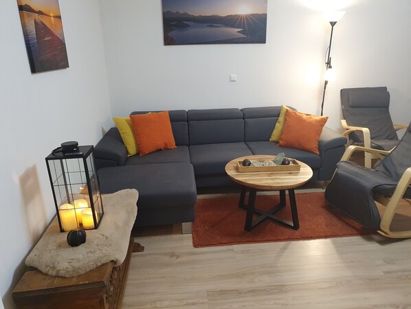 A modern living room with a sectional sofa, a wooden coffee table, and a single armchair.