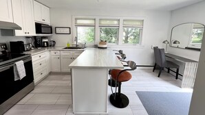 A modern kitchen with white cabinets, a central island, and a dining area with chairs. - Beautiful Brighton/Charlottetown; 1300 sq ft. apartment with AC and large deck.  (Charlottetown)