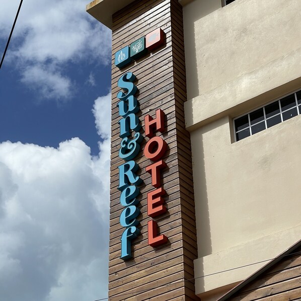 Letrero de hotel con el nombre "Sunreef Hotel" en un revestimiento de madera.