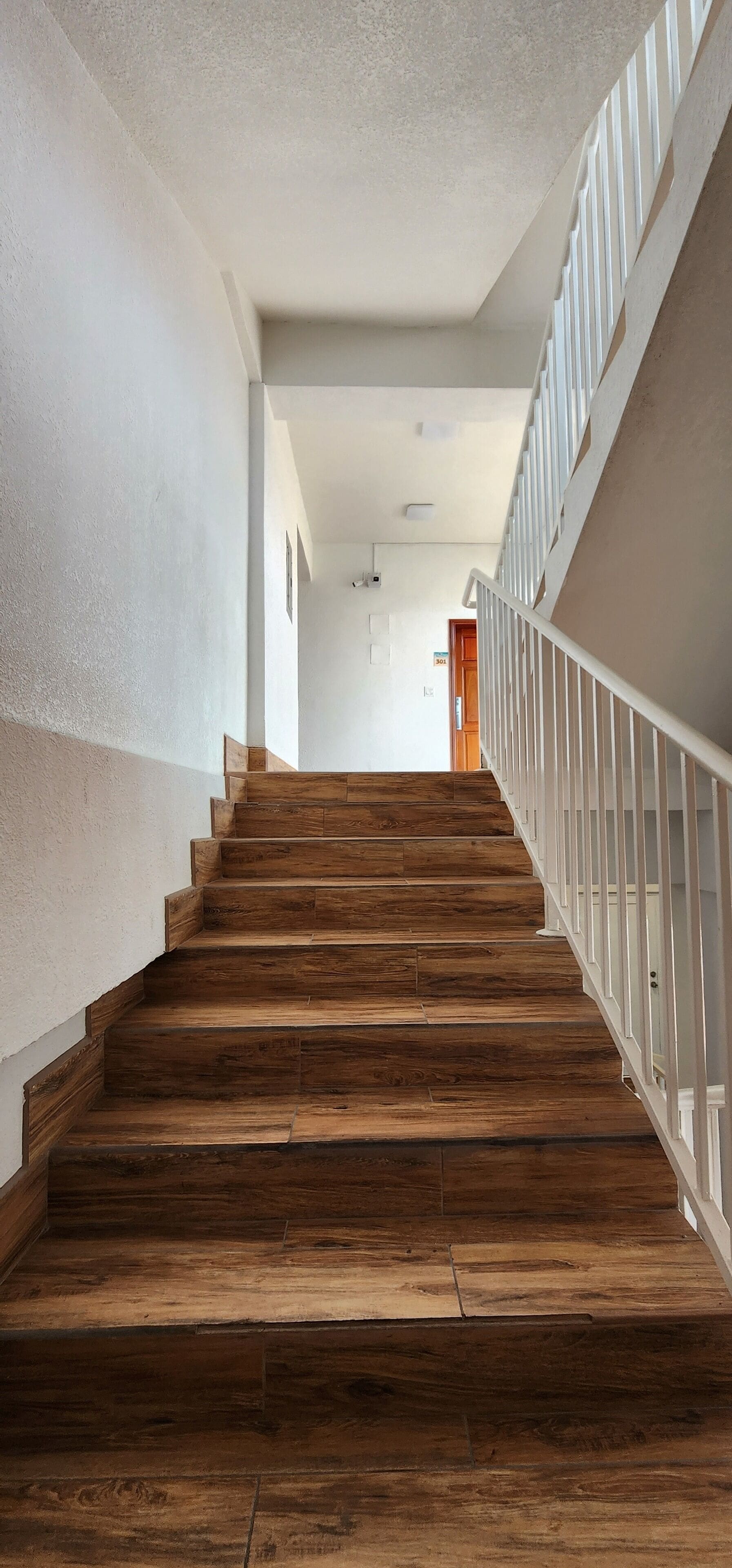 A wooden staircase with white railings leading to a door at the top.