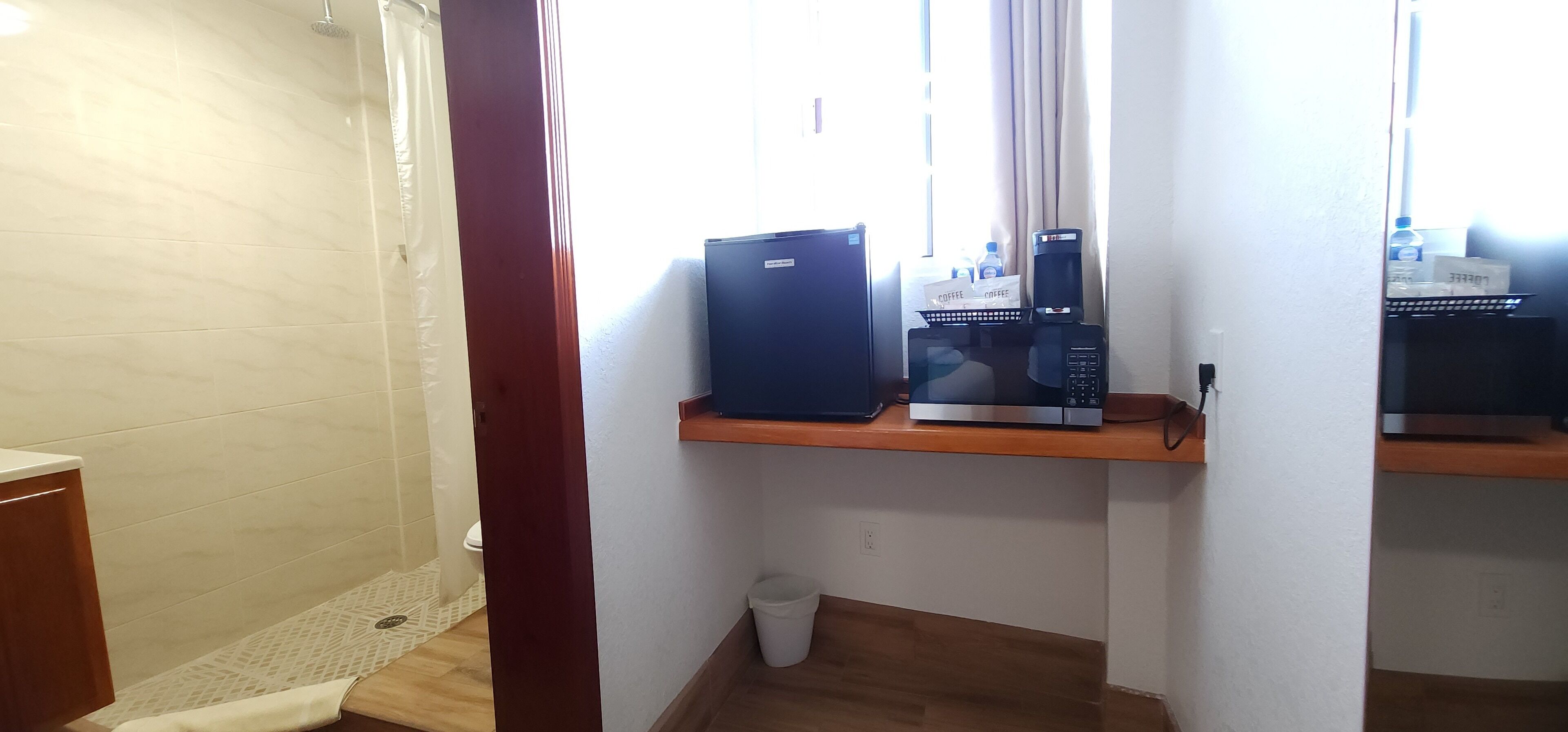 A bathroom with a shower, a toilet, a sink, and a shelf with a coffee maker and a box.