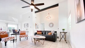A modern living room with a ceiling fan, a round coffee table, a sofa, and a dining area with a chair and table. - LOCATION LOCATION LOCATION Gorgeous Villa Mystique (Palm Springs)