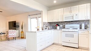 A modern kitchen with white cabinets, a central island, a stove, and a microwave. - LOCATION LOCATION LOCATION Gorgeous Villa Mystique (Palm Springs)
