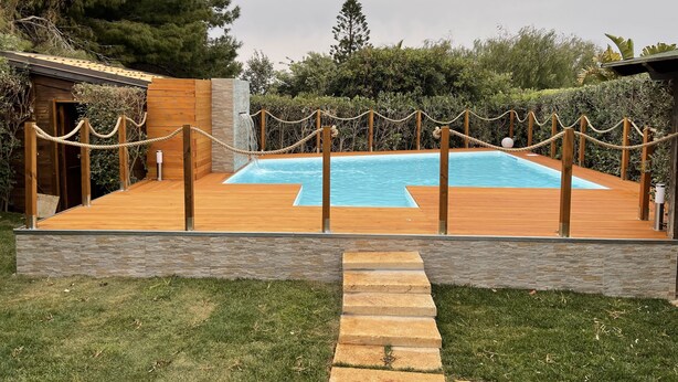 A wooden deck with a swimming pool, surrounded by a rope barrier and stone steps leading to a wooden door. - Villa with pool and with sea view (San Vito Lo Capo)