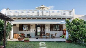 A two-story building with a balcony, outdoor seating area, and a garden path. - Villa with pool and with sea view (San Vito Lo Capo)