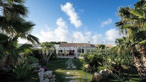 A house with a covered patio, surrounded by lush greenery and palm trees. - Villa with pool and with sea view (San Vito Lo Capo)