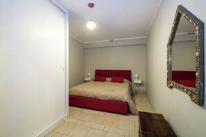 Un dormitorio con cama, lámparas de noche, un espejo y una pequeña mesa de madera.