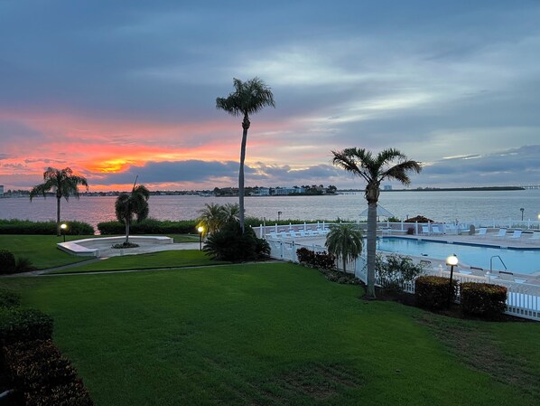 Un espace piscine offrant une vue sur l’eau et le coucher de soleil.