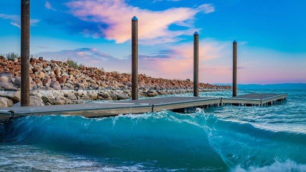 Un molo che si protende nell'oceano, con le onde che si infrangono contro di esso.