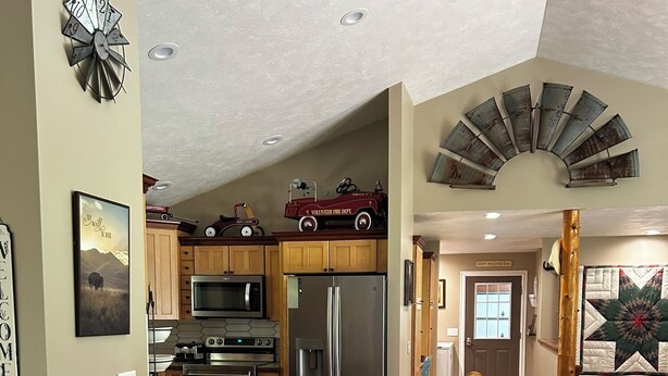 Una cocina amplia con armarios de madera, una isla central con sillas y una pared de acento de piedra.