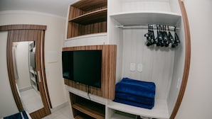 Una habitación con televisión, estanterías de madera, una toalla azul y un zapatero.