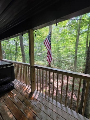 Une terrasse en bois avec une rambarde, un drapeau amĂ©ricain et une vue sur une forĂȘt.