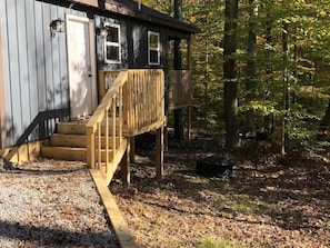 Une cabane en bois dotée d’une terrasse en bois et d’un escalier menant à une porte.