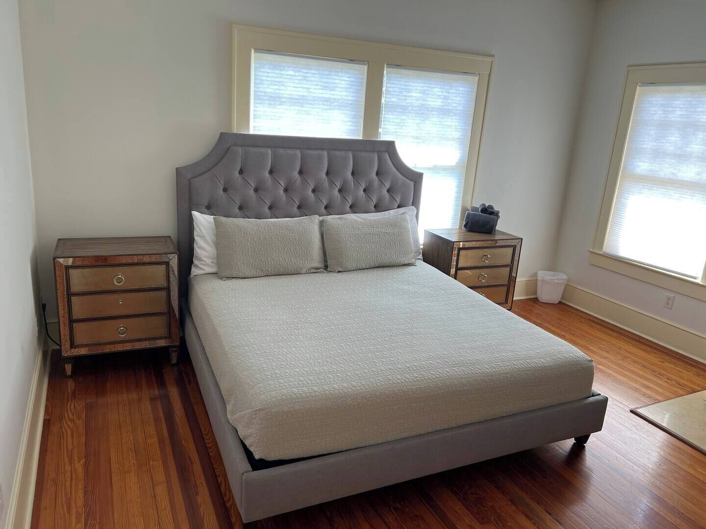 A bedroom with a large bed, two nightstands, and a window with blinds.