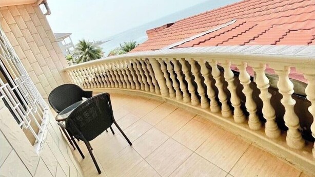 Ein Balkon mit Fliesenboden, einem Stuhl und einem Geländer.