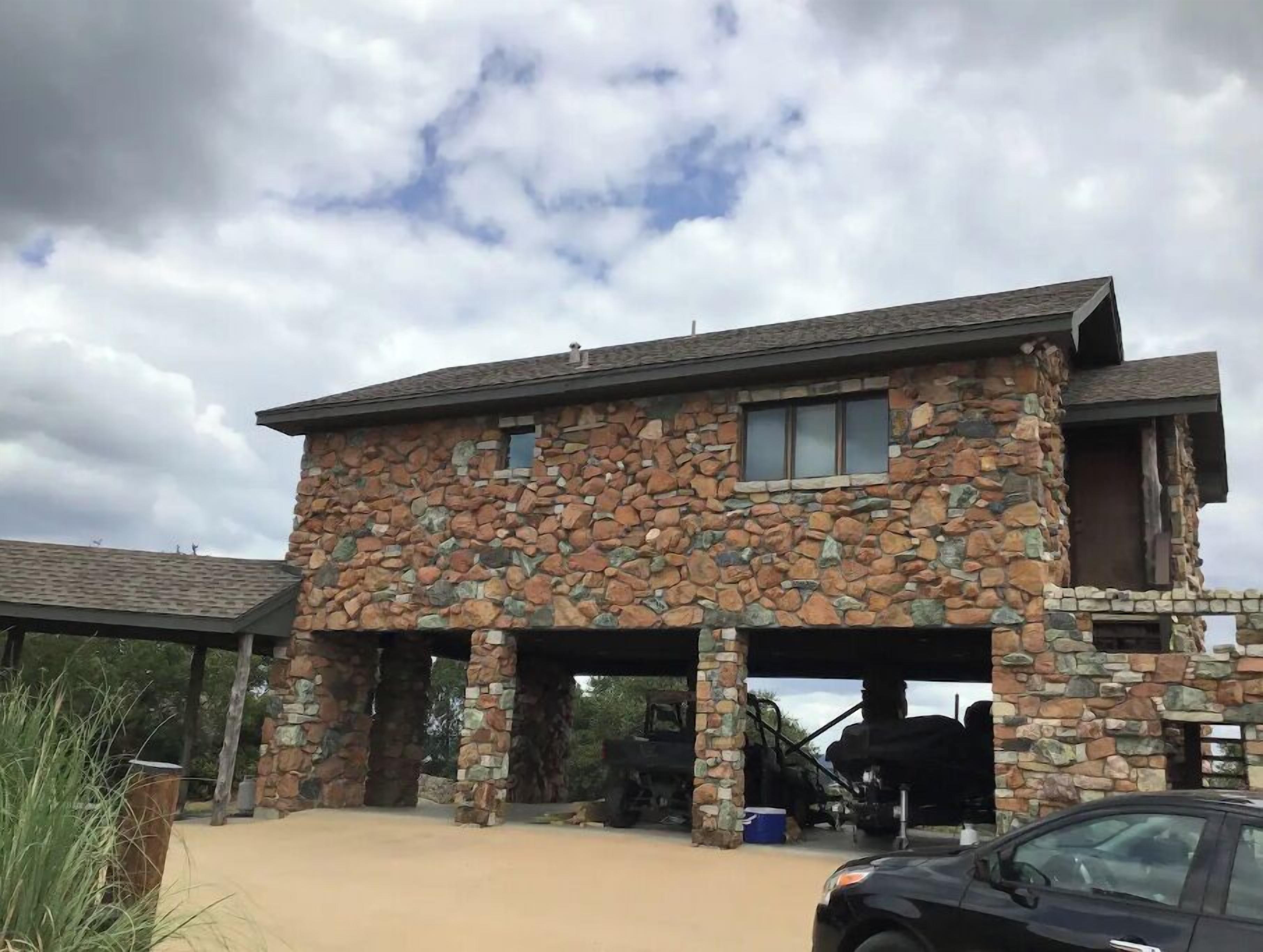A stone building with a covered garage and a car parked in front.