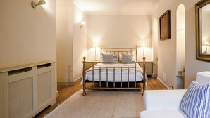 A bedroom with a bed, bedside lamps, a radiator, a sofa, and a mirror. - Stylish coastal living with sea views make this a great choice for your break. (Hunstanton)