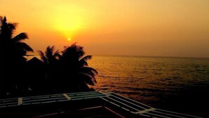 Ein Sonnenuntergang über einem Strand mit Palmen und einem Steg.