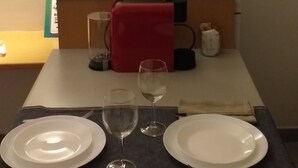 Ruokailutila, jossa on kahdelle katettu pöytä, mikroaaltouuni ja punainen pyyhe hyllyllä.