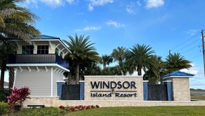 Schild für das Windsor Island Resort mit einem modernen Gebäude und Palmen.
