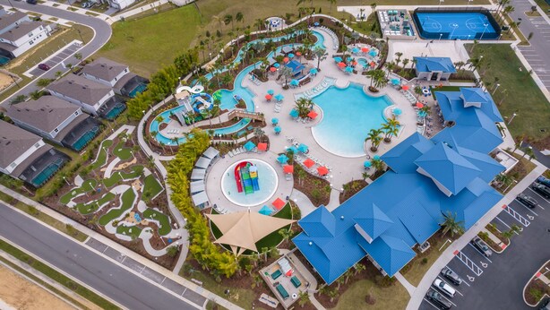 Eine Vogelperspektive zeigt ein Resort mit einem großen Schwimmbecken, Wasserrutschen und einem Parkplatz.